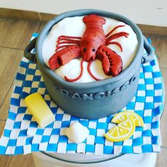 there is a cake that looks like a lobster in a pot with lemons on the side