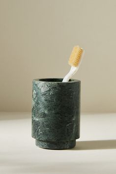 a toothbrush in a green cup on a table