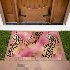 a pink and gold door mat sitting on top of a green lawn next to a wooden door