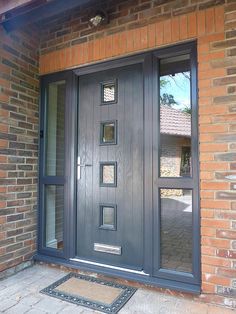 the front door is made of wood and has glass panels on each side, along with an entry mat