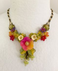 We call this color Caliente with its colorful tones of purple, yellow, red, fuchsia and lime. This necklace has a central flower with clusters of smaller flowers that are either polymer clay or hand painted resin. They are all hand beaded together with 3 tiny ball drops all hand beaded with seed beads. The chain it self is also hand beaded. Original, stunning Colleen Toland work of art. This is a quality piece of jewelry that will last a life time. Created by designer Colleen Toland who has been Multicolor Flower Necklace With Flower Decoration, Yellow Flower Necklace With Colorful Beads, Green Flower Necklace With Colorful Beads, Whimsical Multicolor Flower Necklace, Multicolor Flower Pendant Necklace With Colorful Beads, Multicolor Flower Pendant Necklace, Multicolor Beaded Flower Pendant Necklace, Paper Jewellery, Painted Resin