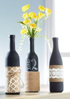 three wine bottles with rope wrapped around them and some flowers in the vase on top