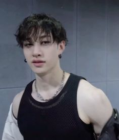 a young man with black hair and piercings on his neck wearing a tank top