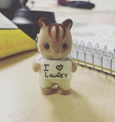 a small toy cat holding a sign that says i love furry on it's chest