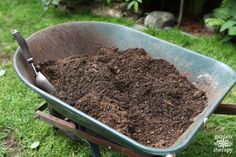 a wheelbarrow filled with dirt sitting in the grass