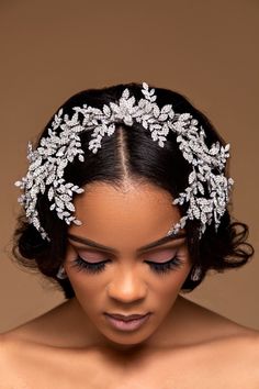 a woman wearing a bridal headpiece with crystal leaves on the side and pearls in the middle