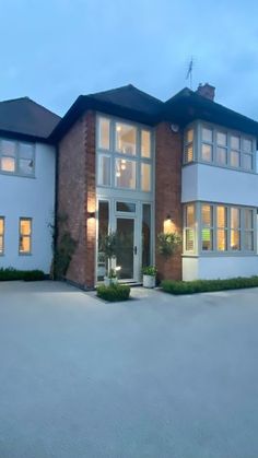 a large white house with lots of windows and plants in the front yard at night