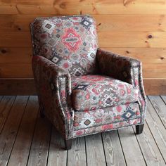 an upholstered chair sits in front of a wood paneled wall and floor