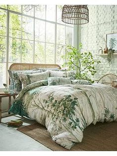 a bed room with a neatly made bed and a plant in the window sill