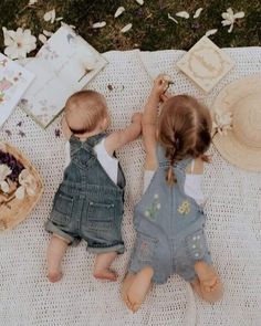 two young children sitting on a blanket with cake and flowers in the backgroud