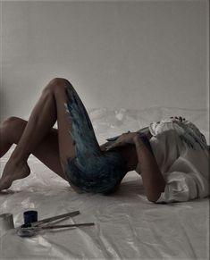 a woman laying on top of a bed covered in paint