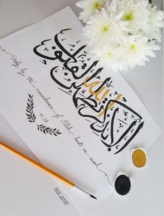 the calligraphy is next to some white flowers and a yellow pencil on a piece of paper