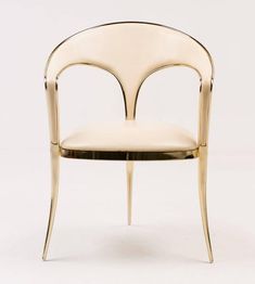 a white chair with gold trim around the armrests and an oval shaped back