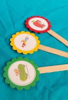 four wooden spoons with pictures on them sitting on a blue cloth covered tablecloth