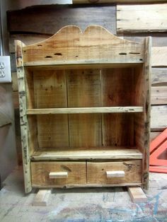 an old wooden bookcase with two drawers on it's sides, sitting in front of some pallets