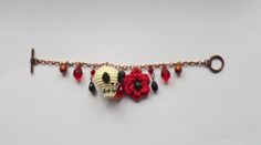 a bracelet with skulls and flowers hanging from it's side on a white wall