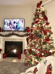 a christmas tree is decorated with red and green ribbon, while the television is on