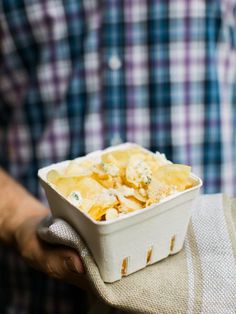 a close up of a person holding a container of food