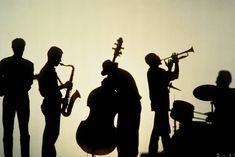 silhouettes of people playing instruments in front of the sun