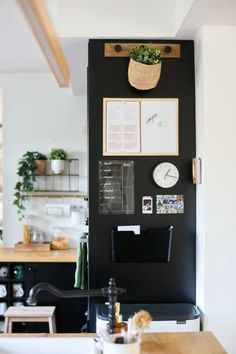 a kitchen with a black wall and clock on the wall next to a wooden table