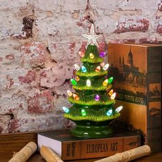 a green glass christmas tree sitting on top of a wooden table next to a book