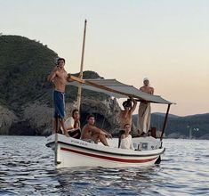 three men are on the back of a boat while one man is taking a photo