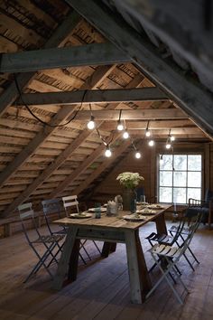 an attic with wooden flooring and lights hanging from the rafters, along with several chairs