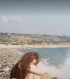 a woman sitting on the beach next to the ocean