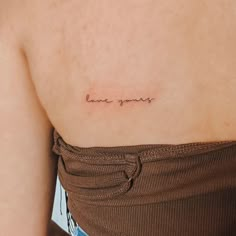 a woman with a small tattoo saying love you on her left side ribcage