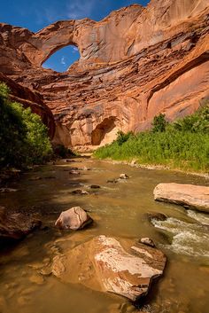 a river flowing through a canyon under a rock formation