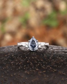 a blue diamond ring sitting on top of a rock