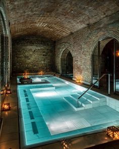 an indoor swimming pool surrounded by candles and stone walls with the words spas on it