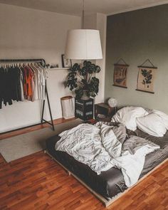 an unmade bed sitting on top of a hard wood floor next to a lamp