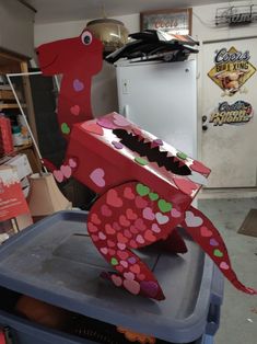 a red paper sea horse on top of a blue trash can in a storage room