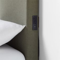 a close up of a bed with a pillow and light switch on the headboard