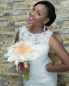 a woman in a white dress holding a bouquet of flowers and posing for the camera