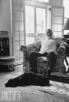 a man sitting on top of a couch in a living room next to a window