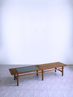 a wooden table sitting on top of a tile floor next to a white wall and tiled floor