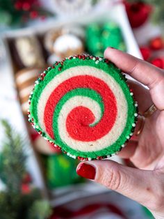 a hand holding up a green, white and red lollipop