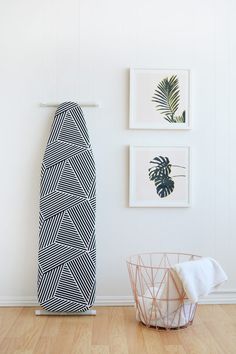 an ironing board next to a basket on the floor in front of a white wall