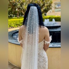 the back of a bride's wedding dress, with her veil draped over her head