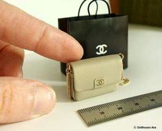 a miniature chanel bag is sitting next to a ruler