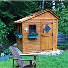 a small wooden shed sitting on top of a lush green field next to a park bench