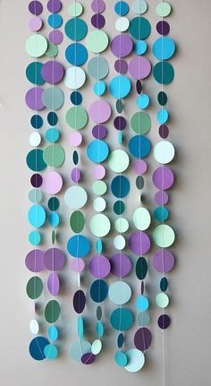 a multicolored paper mobile hanging from a wall with circles and dots on it