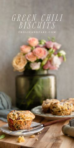 close up picture of fall flaky cheedar bacon green chili biscuit on small plate with green vase with pink roses in the background