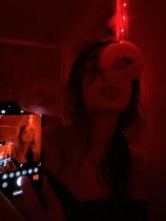 a woman taking a selfie in the dark with her cell phone and red light