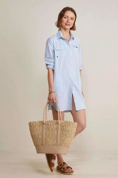 A person standing in front of a beige background wearing a blue and white striped shirt dress Everyday Natural Straw Bag With Leather Trim, Casual Beach Bag With Bamboo Handle For Vacation, Casual Straw Bag With Leather Trim For Travel, Natural Straw Bag With Leather Trim, Casual Style, Everyday Straw Tote Bag With Leather Trim, Everyday Leather Trim Straw Tote Bag, Summer Straw Bag With Leather Trim For Everyday, Casual Straw Bag With Bamboo Handle For Vacation, Casual Beach Bag With Bamboo Handle For Travel