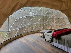 a bed sitting inside of a bedroom next to a large glass window filled with trees