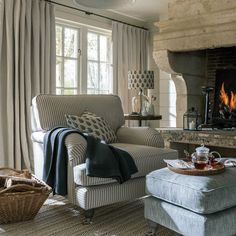 a living room filled with furniture and a fire place next to a window covered in curtains