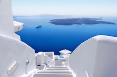 an aerial view of the blue water and white buildings in oia, with a cruise ship in the distance